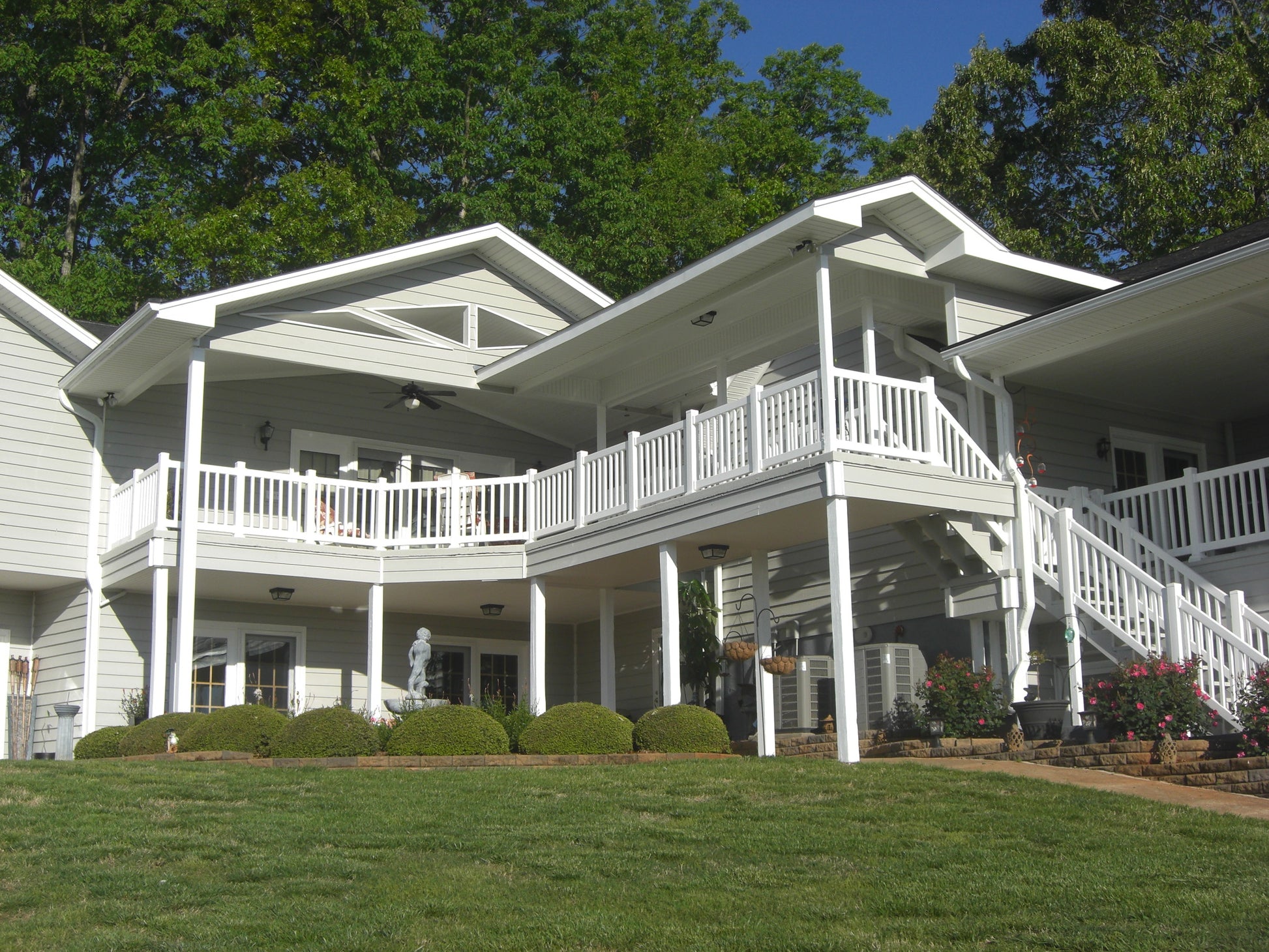 Large white house with multiple porches, Weatherables Berkshire white vinyl deck railing and a well-maintained lawn.