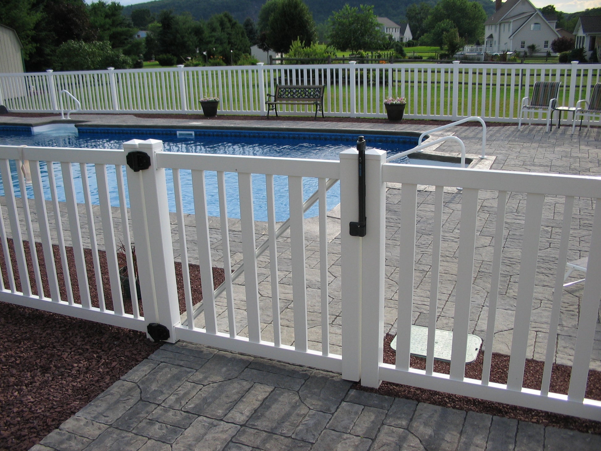 Weatherables Atlantis white vinyl pool gate with a view of a swimming pool and patio area.