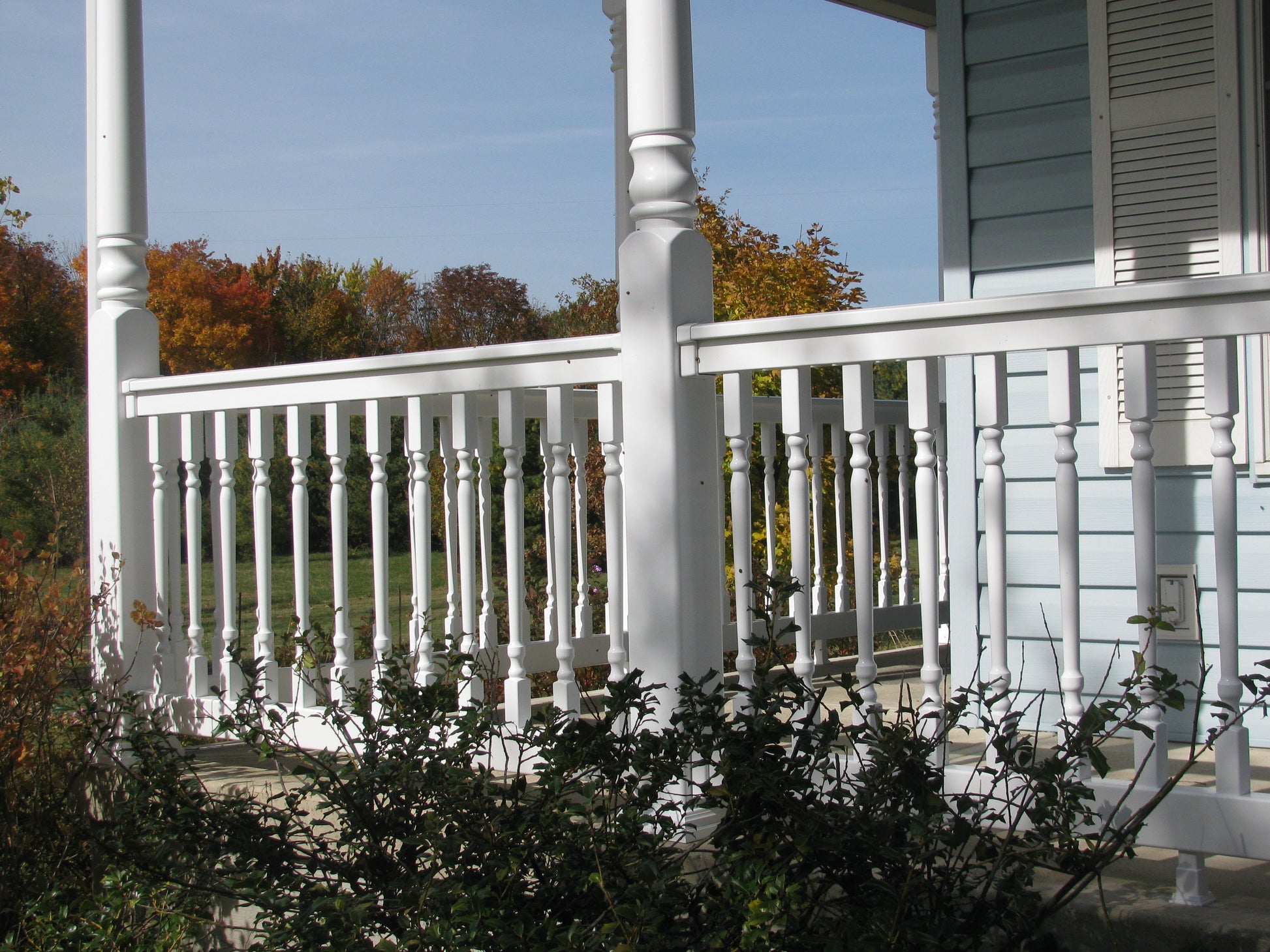 White porch with Weatherables Addison white vinyl porch railing and columns on a sunny day