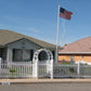 Weatherables Hampshire white vinyl picket fence in front of a house with an American flag on a clear day.