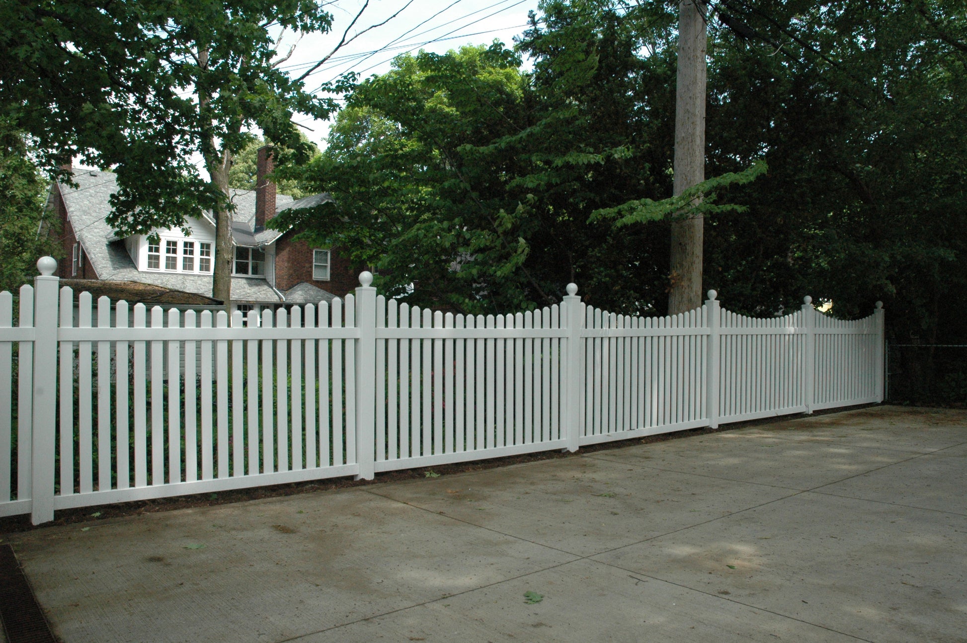 Weatherables Richmond white vinyl picket fence with a house and trees in the background