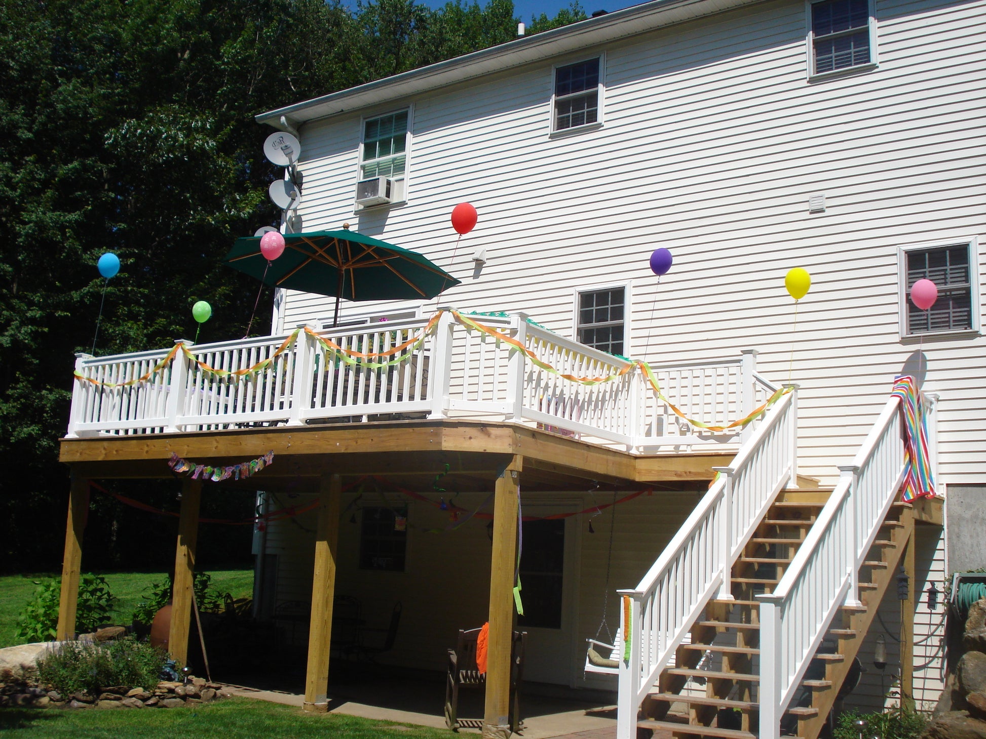 White house with a decorated Weatherables Washington white vinyl deck railing featuring colorful balloons and an umbrella.