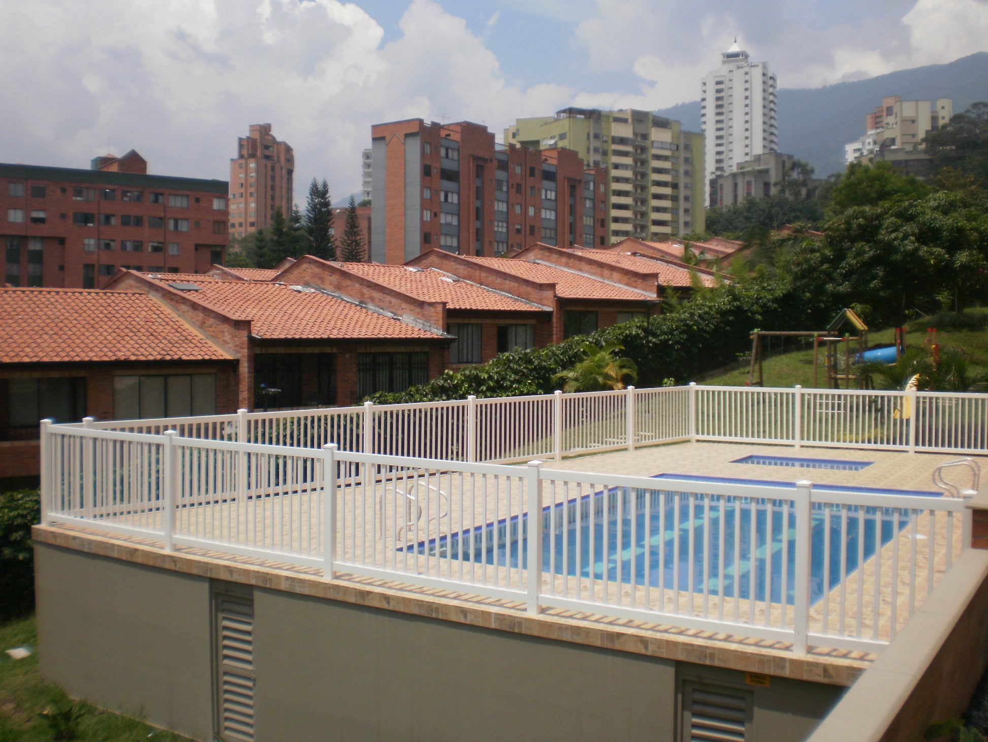 Pool area with Weatherables Neptune white vinyl closed-top picket fencing and surrounding buildings in the background