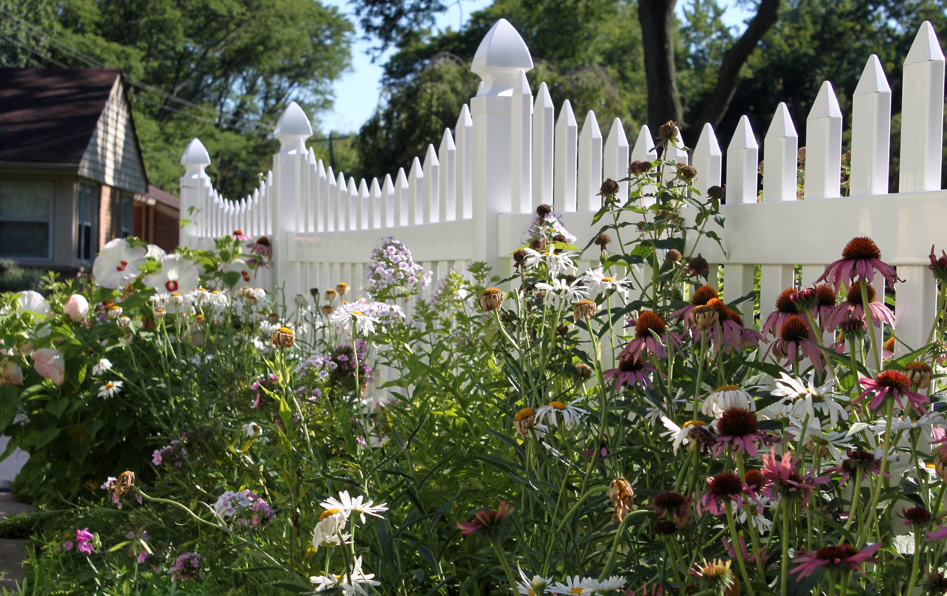 Weatherables Ellington white vinyl picket fence with a garden of flowers in the foreground