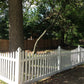 Weatherables Hampshire white vinyl picket fence with trees and a wooden fence in the background