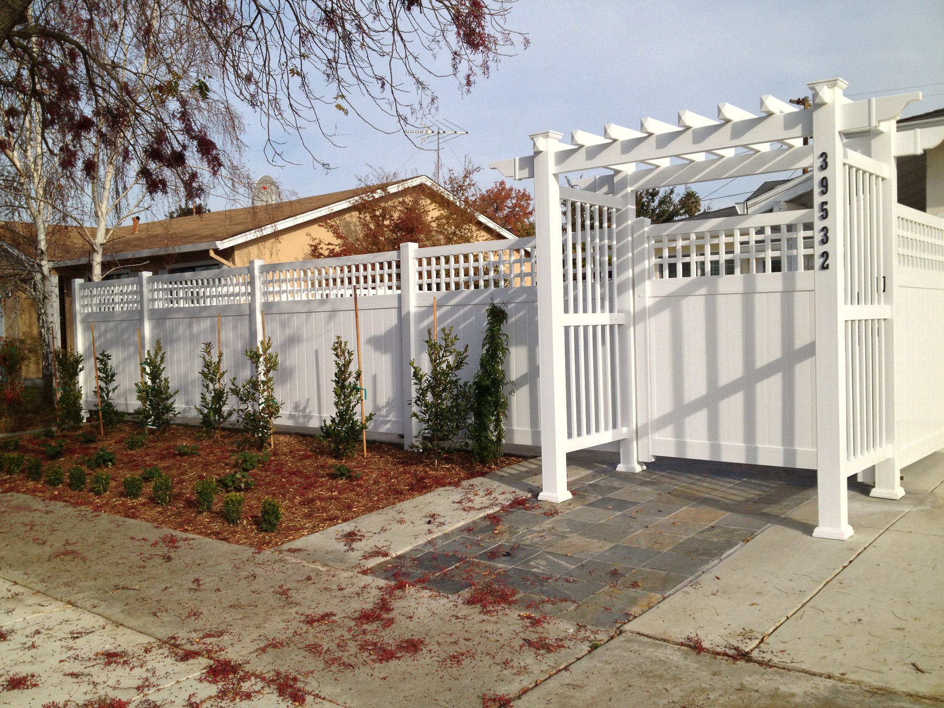 White pergola with lattice design on a residential property with Weatherables Scottsdale white vinyl privacy fence