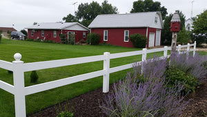 Red barn with Weatherables 2-rail white  vinyl horse fence and green grass