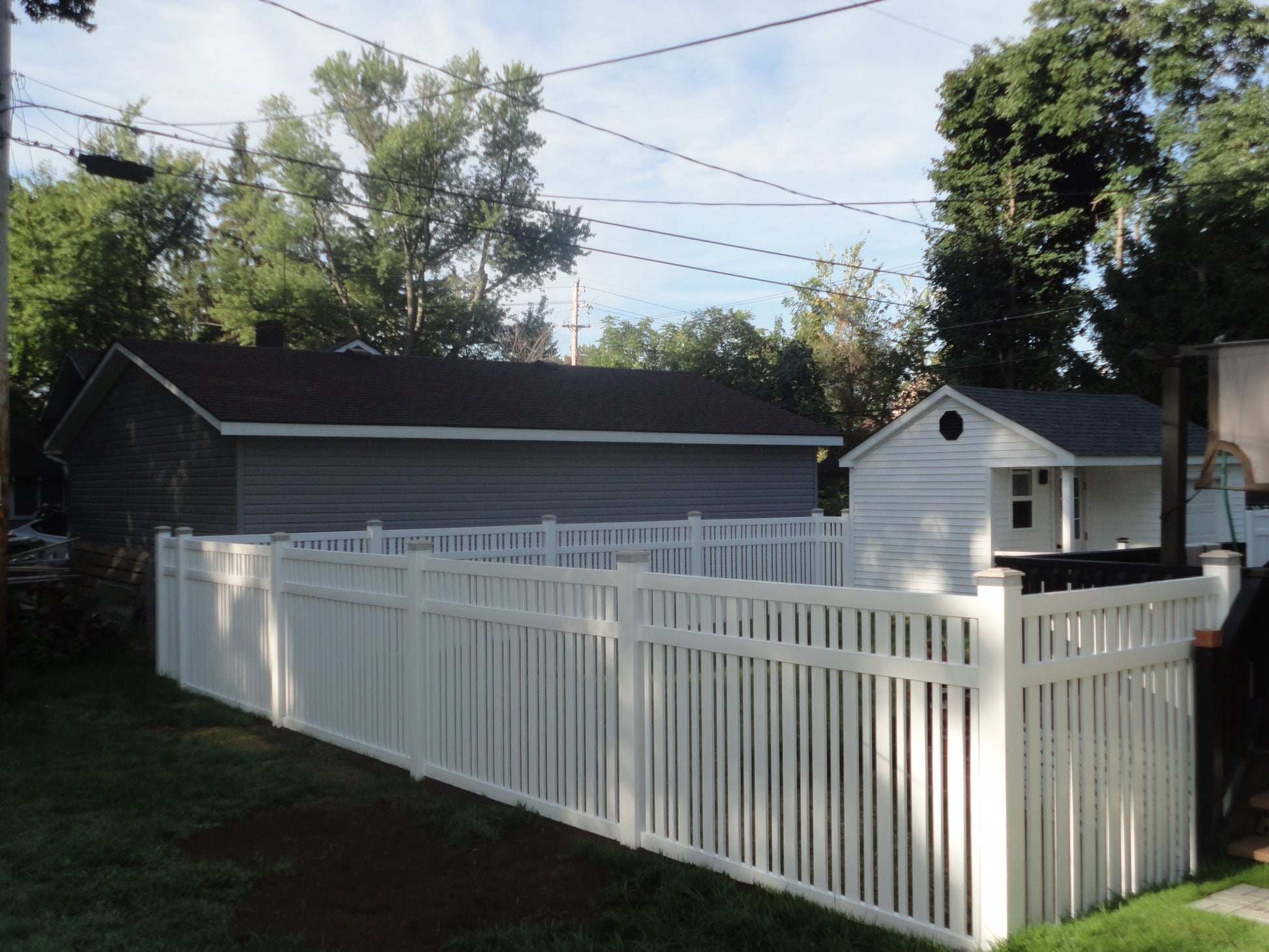 Weatherables Sarasota white vinyl pool fence with a house and trees in the background
