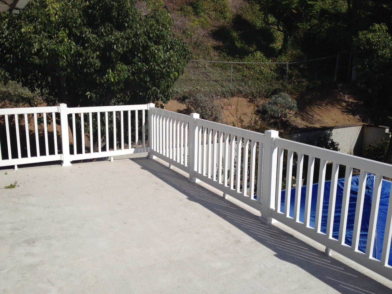 Weatherables Berkshire white vinyl porch railing on a deck with a view of trees and a pool.