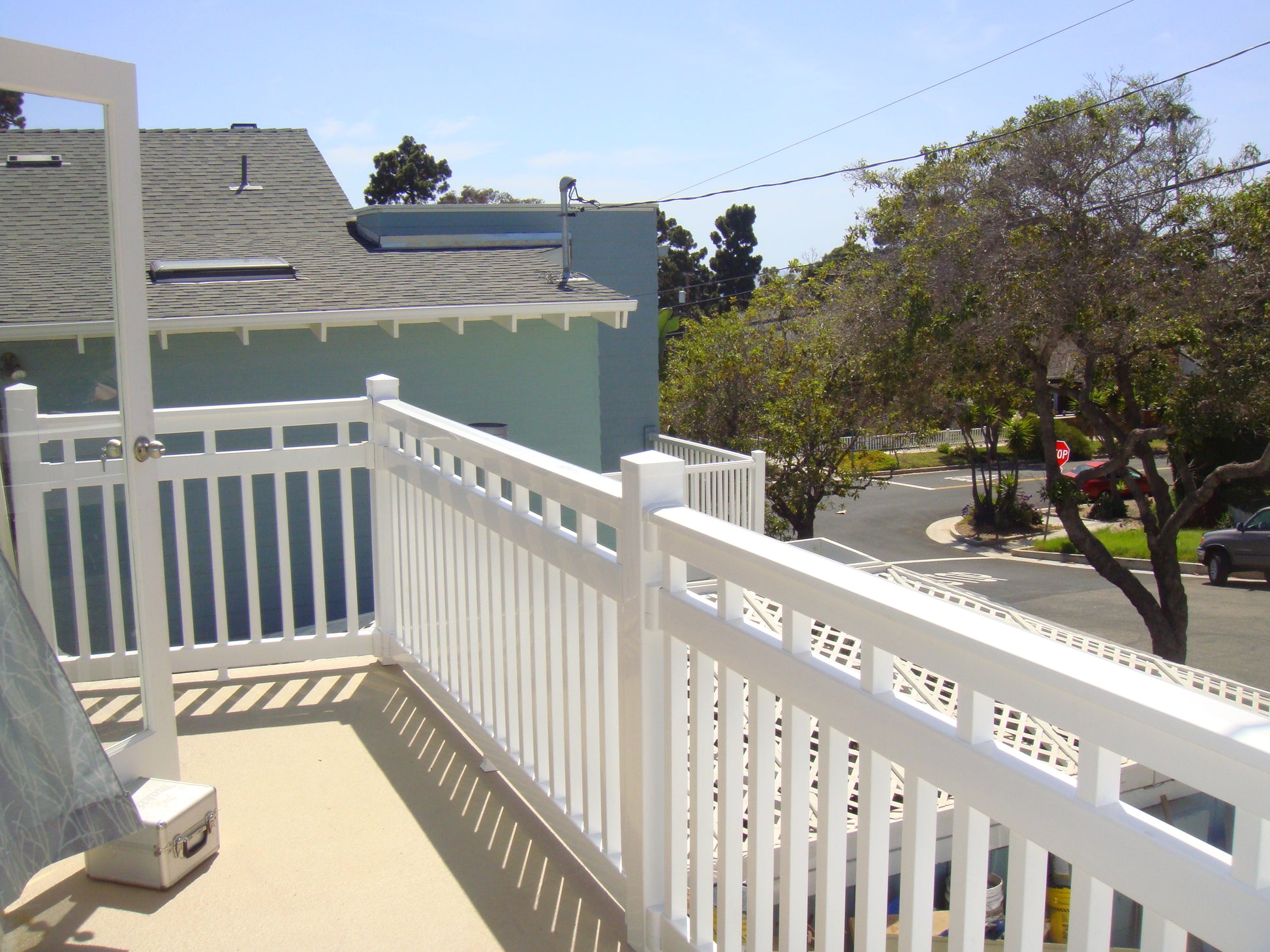 Balcony with Weatherables Cheshire white vinyl deck railing overlooking a street with trees and buildings.