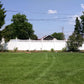 Lawn with a Weatherables Halifax white vinyl privacy fence and trees under a blue sky