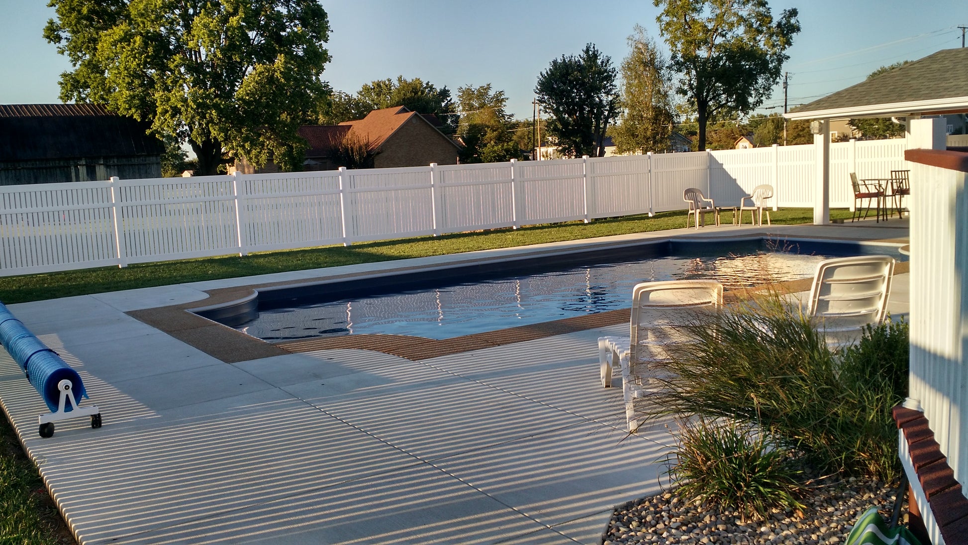 Pool area with a Weatherables Huntington white semi-privacy fence, trees, and a clear sky.