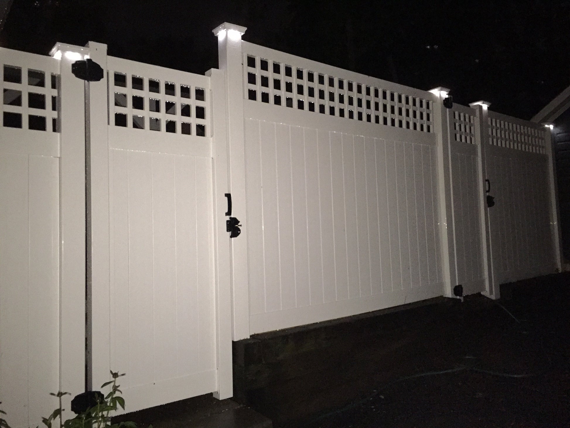 Weatherables Scottsdale white vinyl privacy fence with light fixtures at night