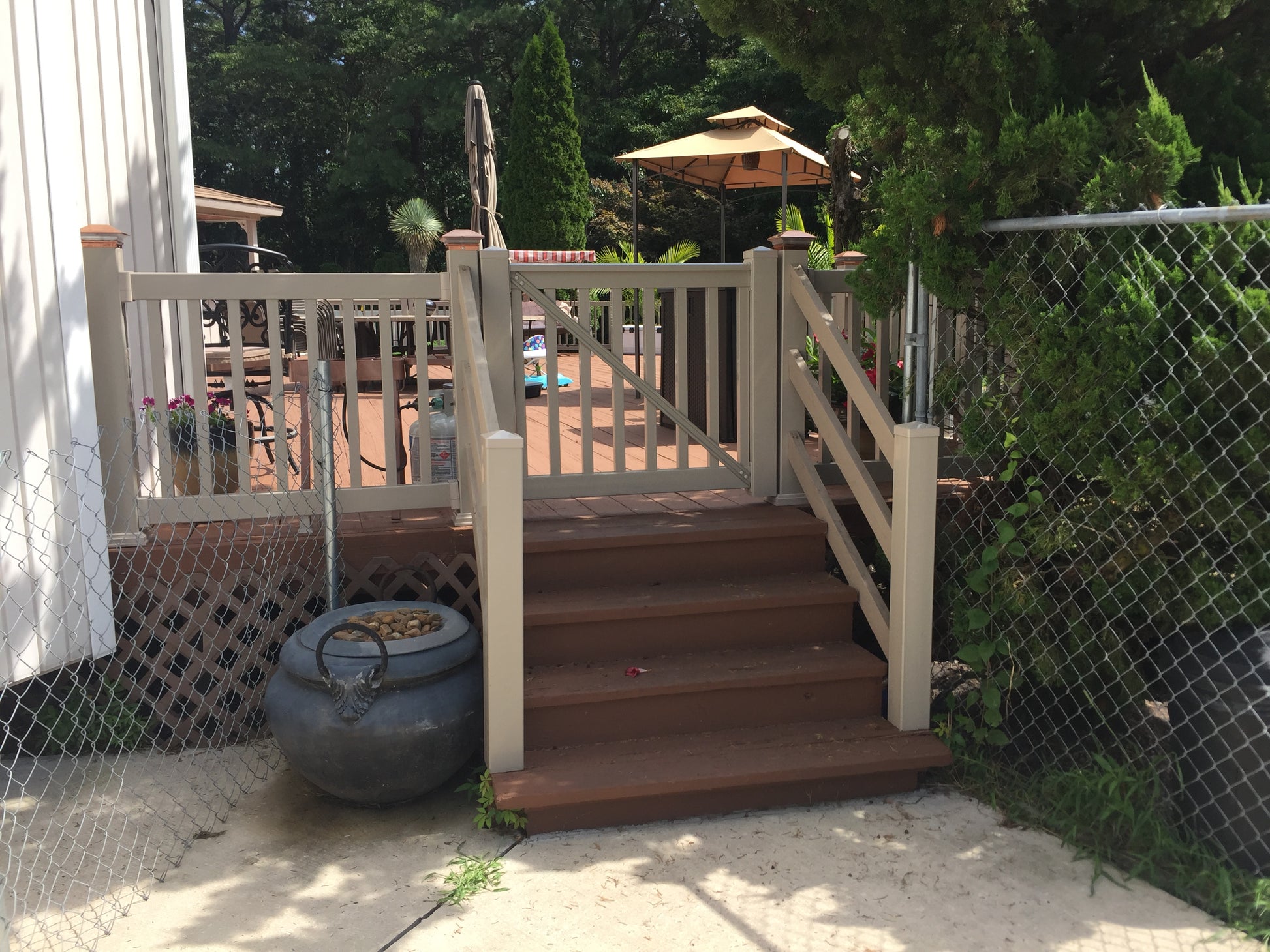 Wooden steps leading to a deck with a garden and Weatherables Berkshire khaki vinyl deck railing in the background