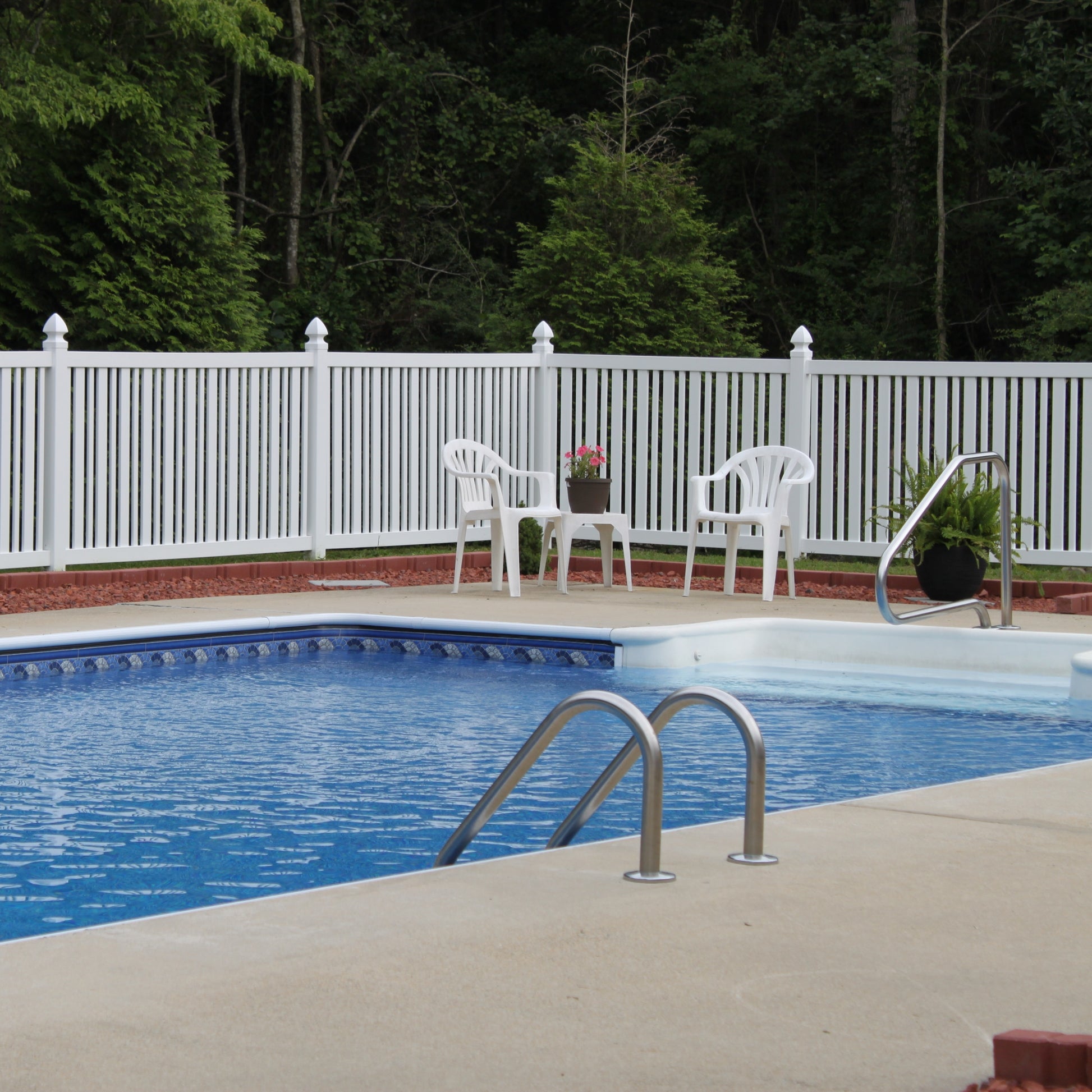 Pool area with white chairs, a table, and a Weatherables Sarasota white vinyl closed-top picket fence in the background