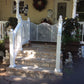 Front porch with Weatherables Addison  white vinyl deck railing, stone steps, and decorative elements on a sunny day.