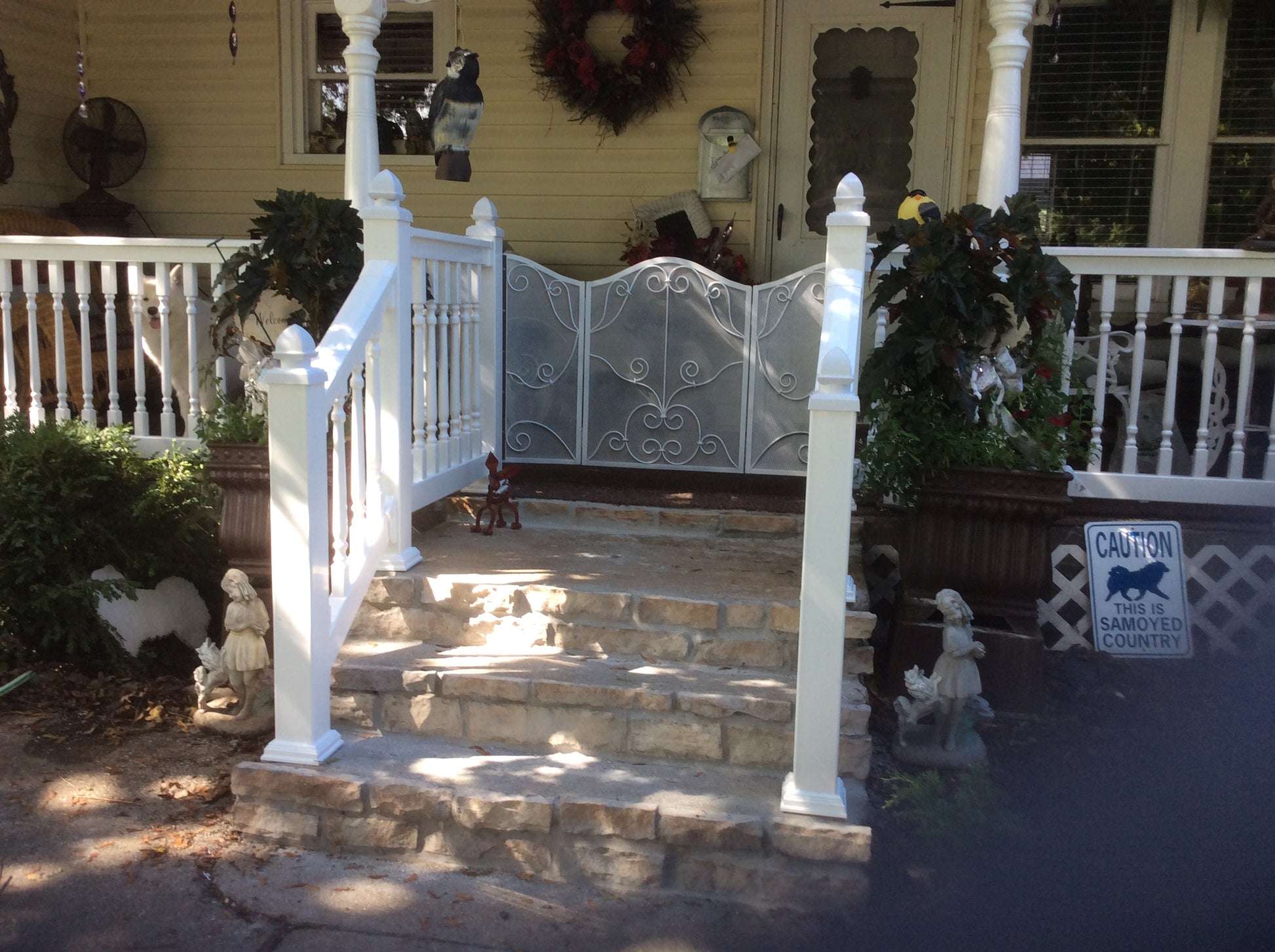 Front porch with Weatherables Addison  white vinyl deck railing, stone steps, and decorative elements on a sunny day.