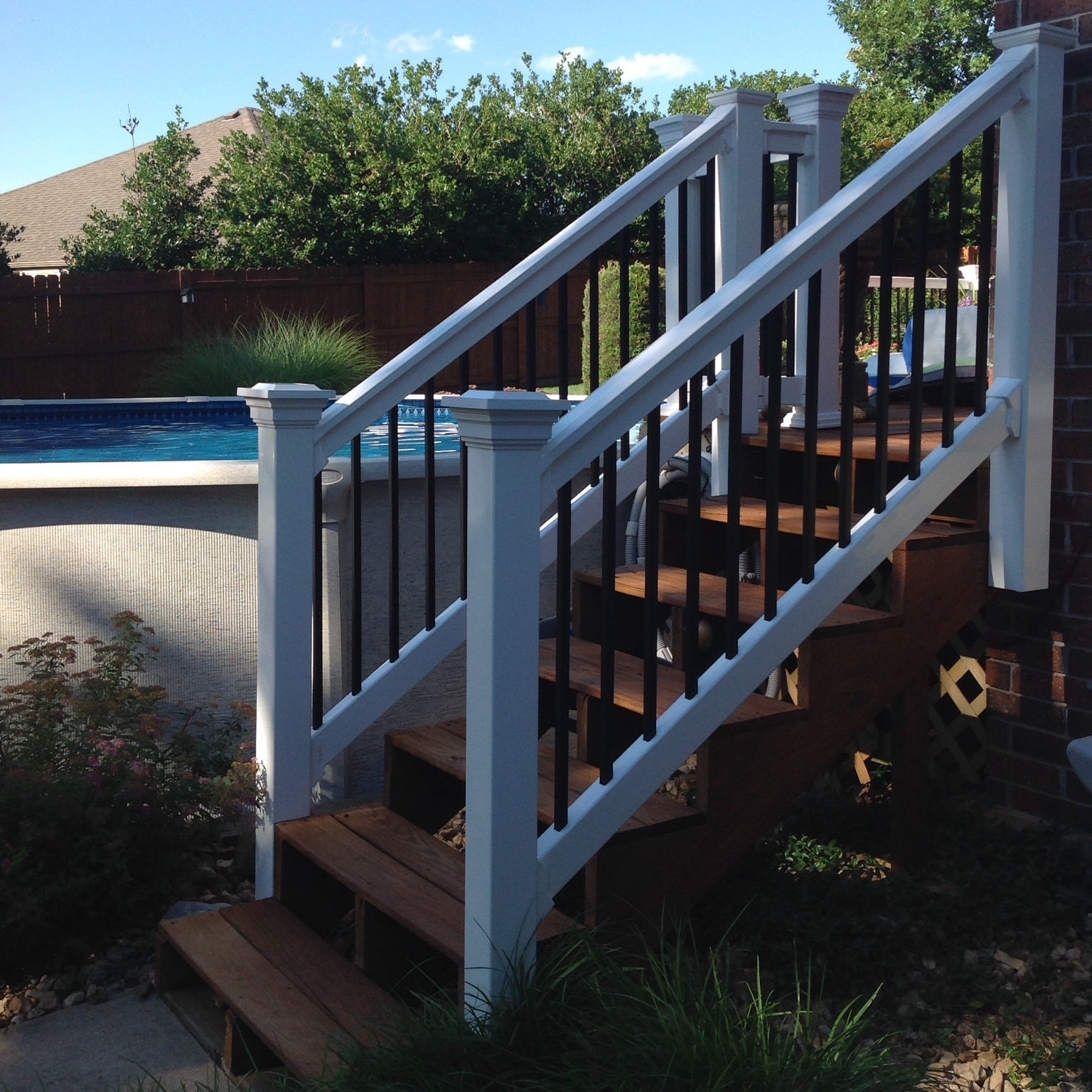 Wooden deck with white railing leading to a pool area