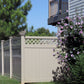 Weatherables Ashton khaki vinyl privacy fence with lattice design, greenery, and a flowering bush in front of a house.