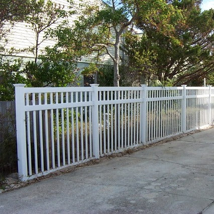 Weatherables Neptune white vinyl pool fence along a sidewalk with trees and a house in the background