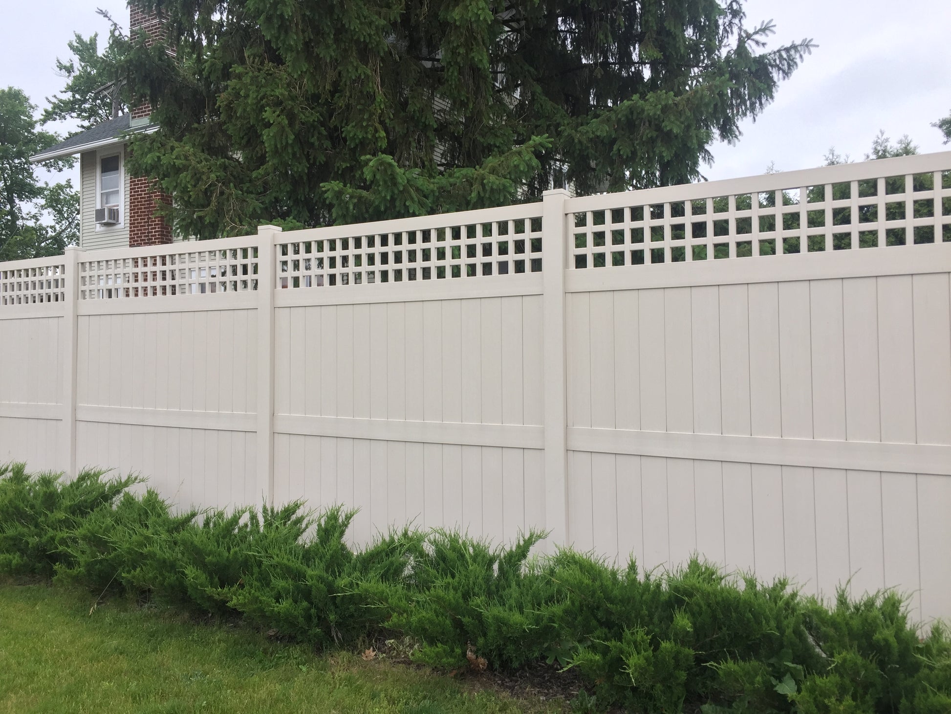 Weatherables Scottsdale tan vinyl privacy fence with lattice top in a residential setting