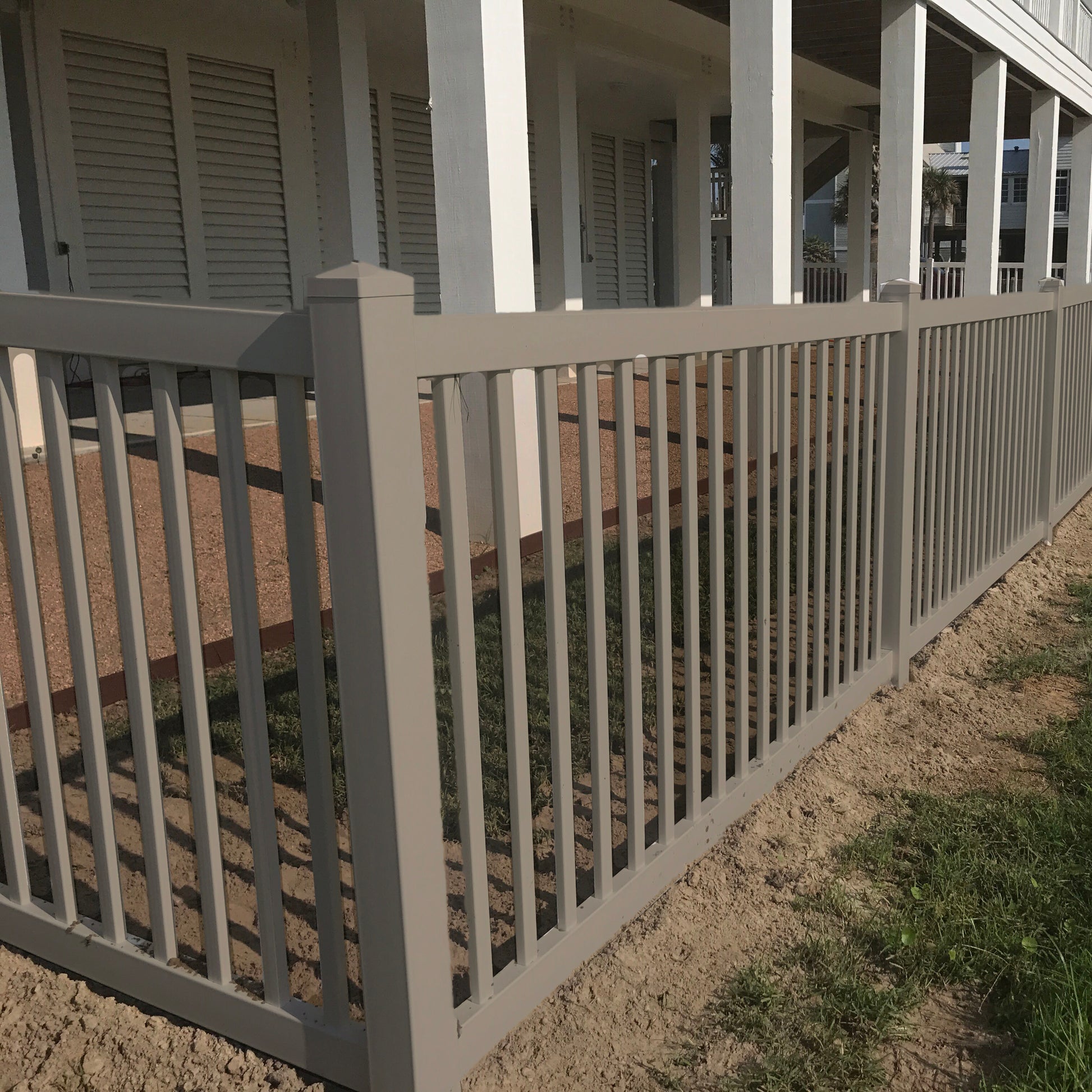 Weatherables Captiva khaki vinyl pool fence in front of a house with a porch