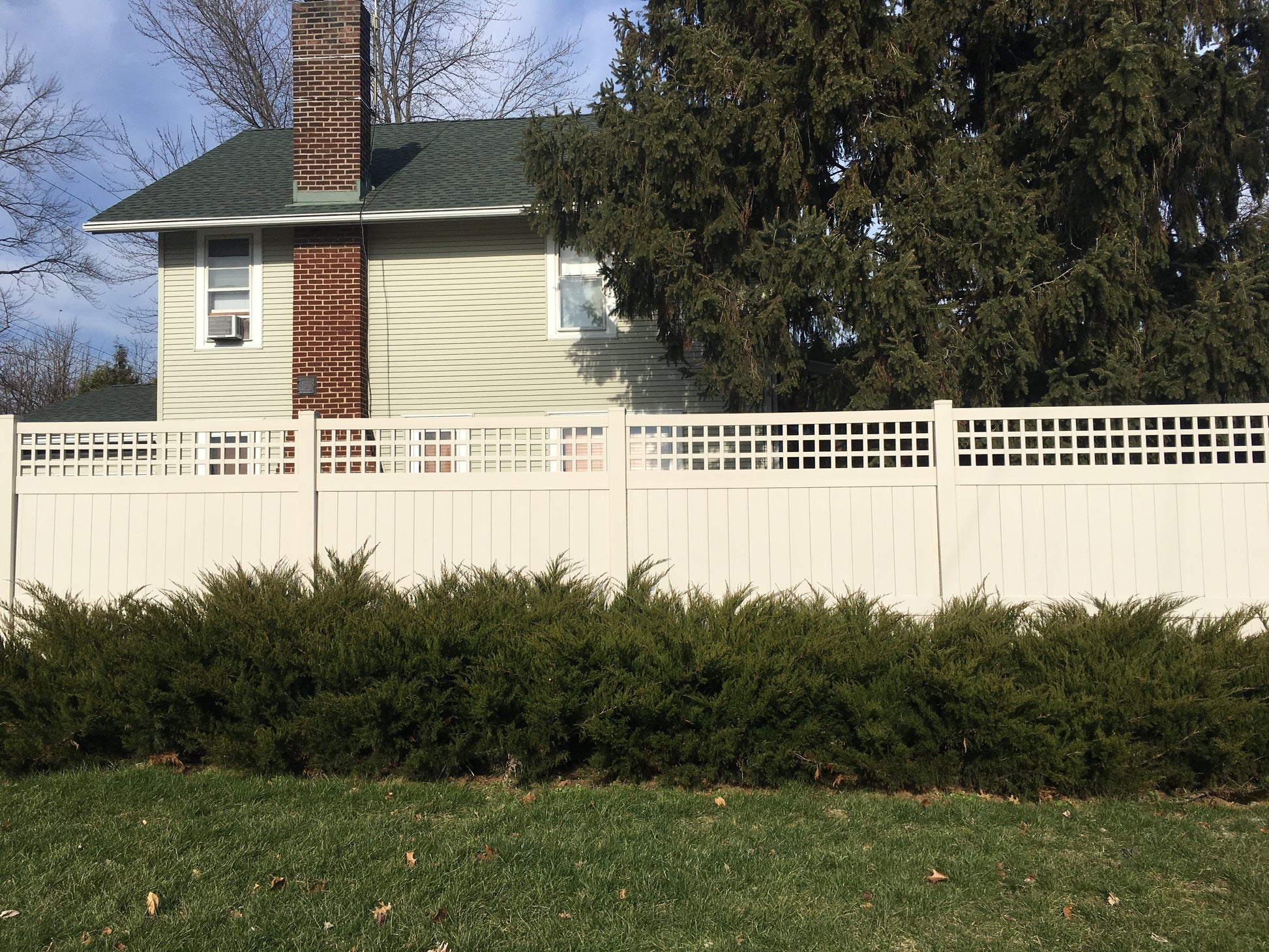 House with a Weatherables Scottdale tan vinyl privacy fence and greenery in front