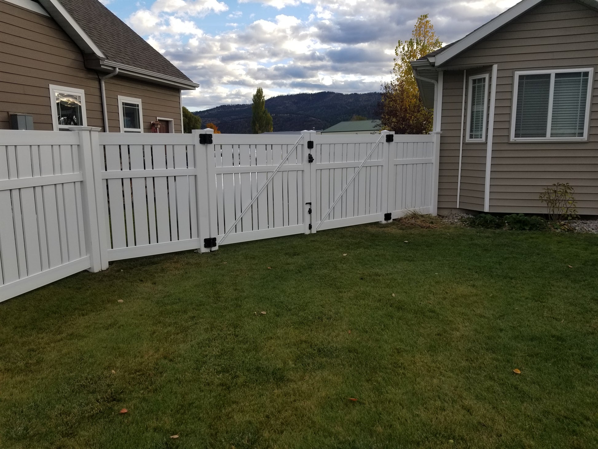 Weatherables Alden white vinyl semi-privacy fence between two houses with a scenic background