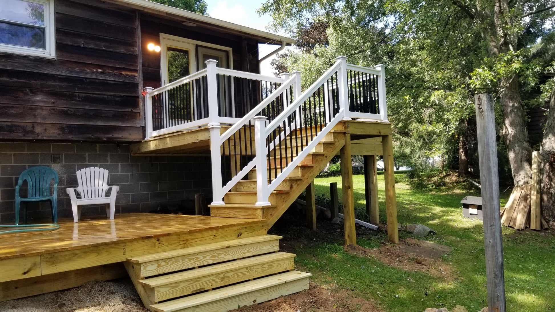Wooden deck with Weatherables Birmingham white vinyl stair railings leading to a house, surrounded by greenery.