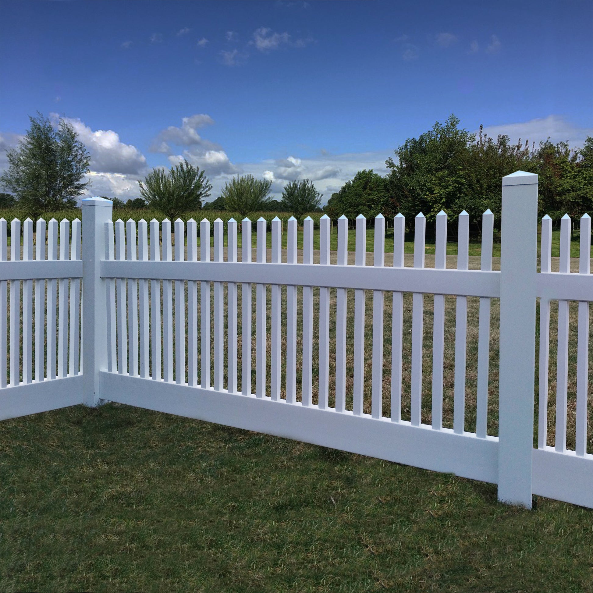 Weatherables Monteray white vinyl picket fence with a grassy area and trees in the background