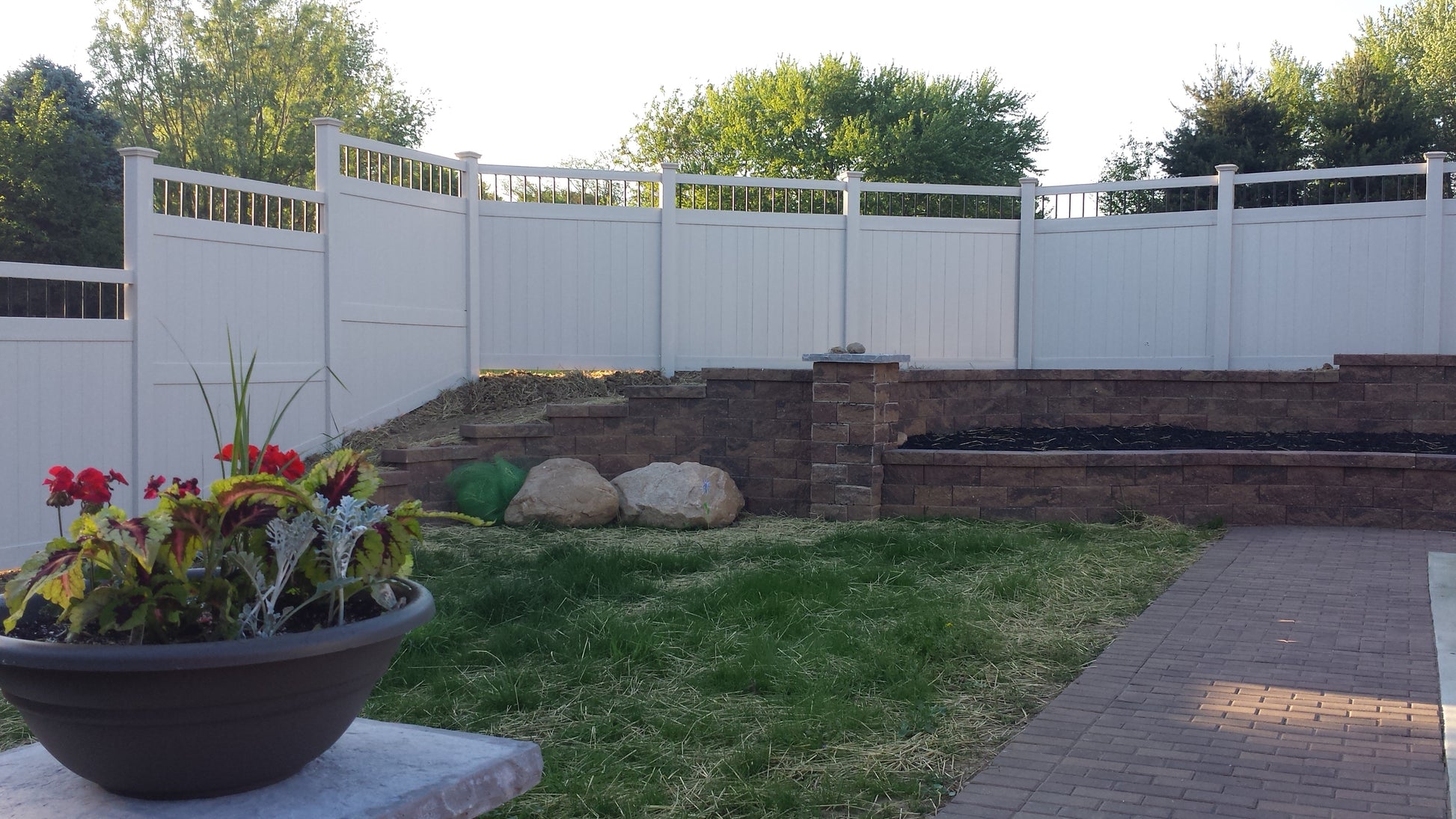 Backyard with a Weatherables Bradford 8-foot tall white vinyl privacy fence, garden, and stone pathway