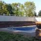 Pool area with a Weatherables Bradford white vinyl privacy fence, trees, and a potted plant.