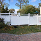 Weatherables Mason white vinyl privacy fence in a residential backyard with trees and a clear sky.