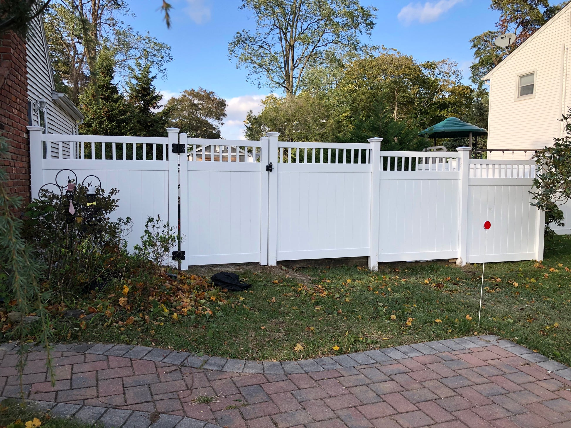 Weatherables Mason white vinyl privacy fence in a residential backyard with trees and a clear sky.