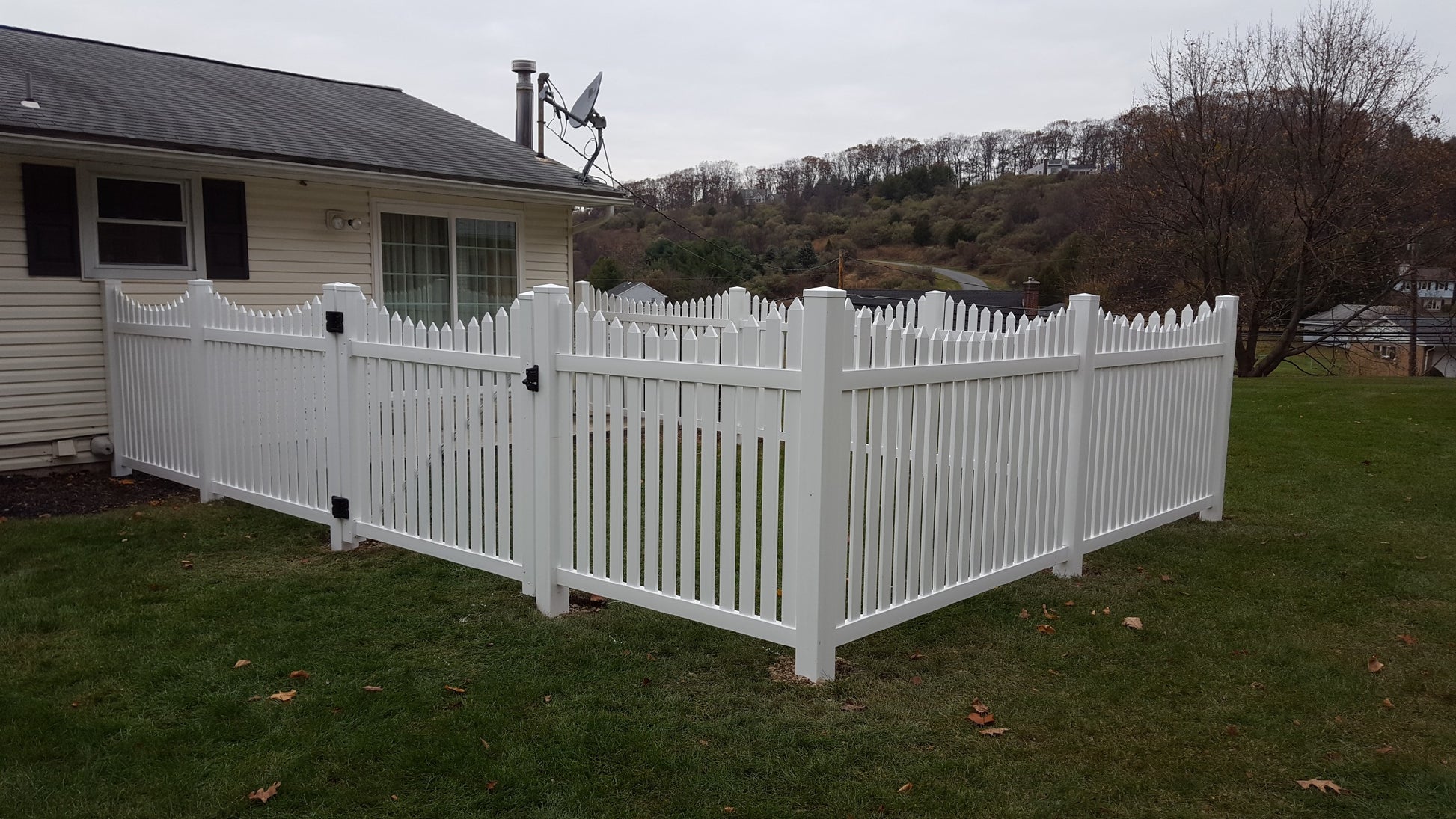 Weatherables Richmond white vinyl picket fence in front of a house with a cloudy sky