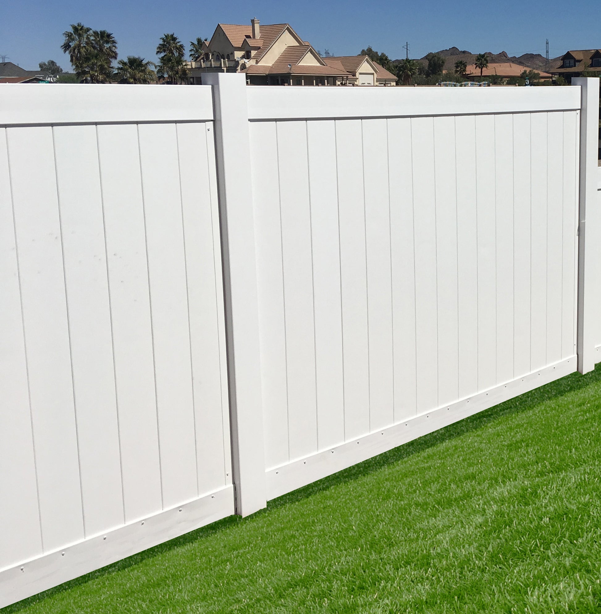 Weatherables Pembroke white vinyl privacy fence with green grass and houses in the background