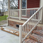 Front porch with Weatherables Yorkshire tan vinyl deck railing and steps leading to a house, with construction materials on the ground.