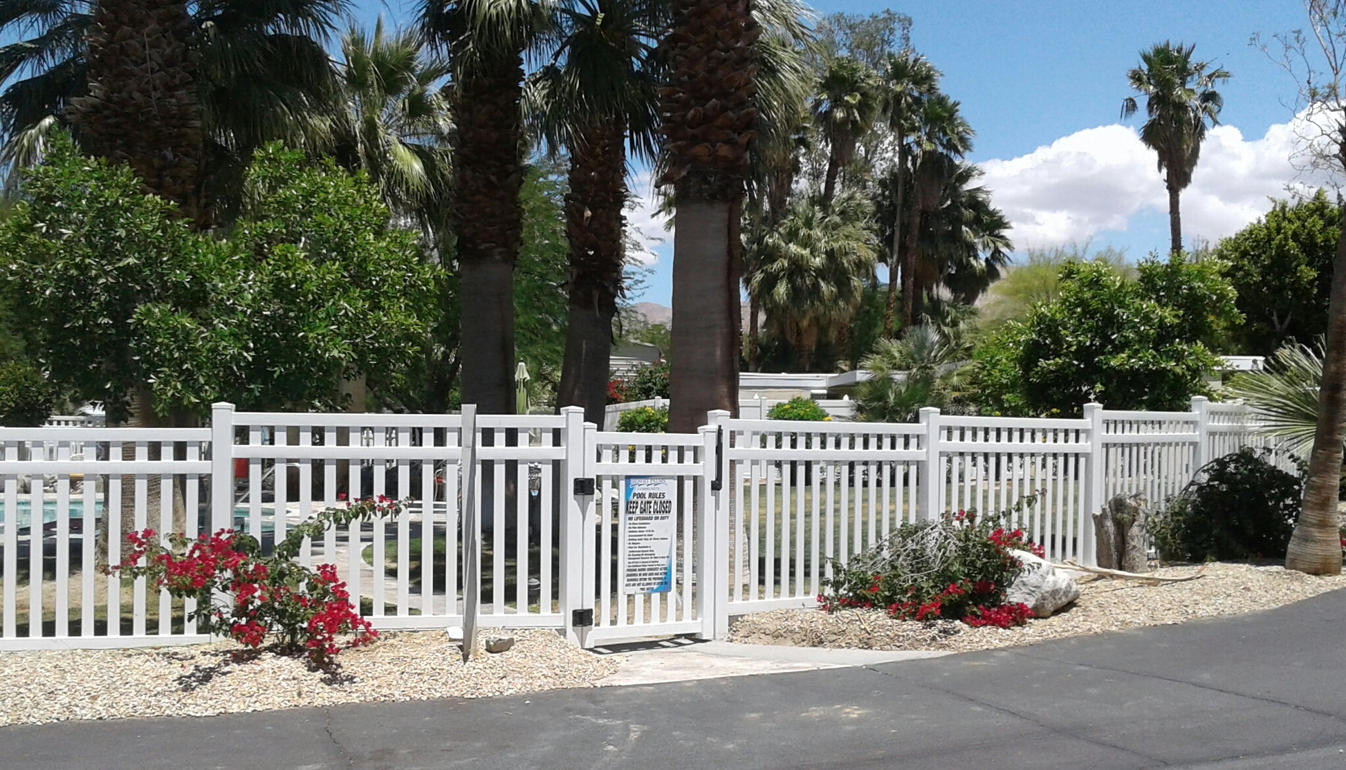 Weatherables Captiva white vinyl pool fence with flowers and palm trees in the background