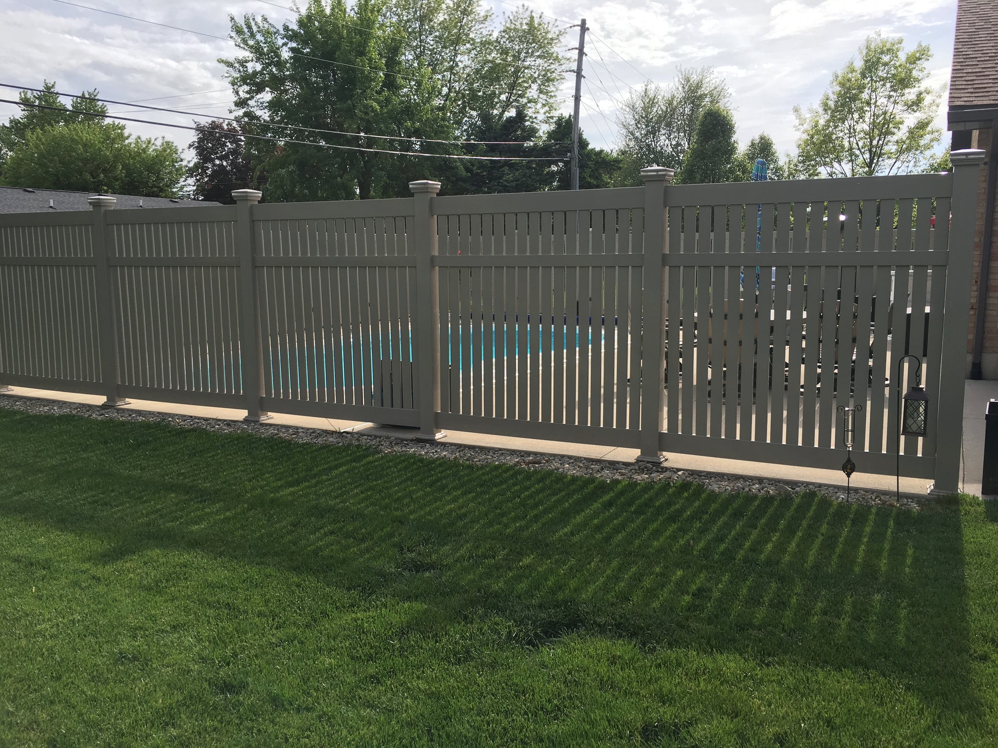 Weatherables Huntington Khaki vinyl semi-privacy fence with a gate in a backyard setting