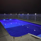 Pool at night with illuminated deck and Weatherables Sarasota white vinyl pool fence and LED lighting post caps