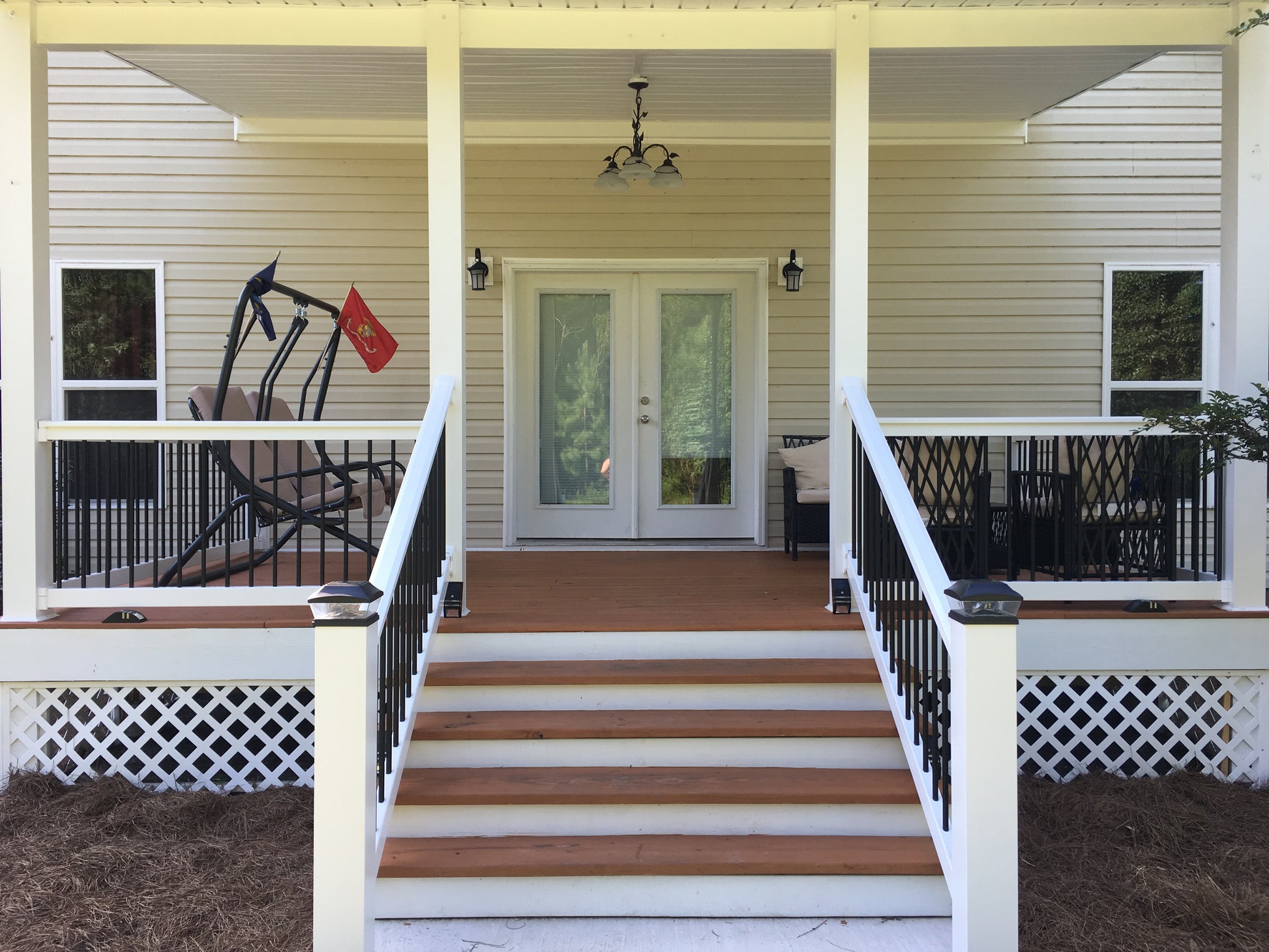Front porch of a house with Weatherables Wiltshire white vinyl deck railing on wooden steps leading to the door