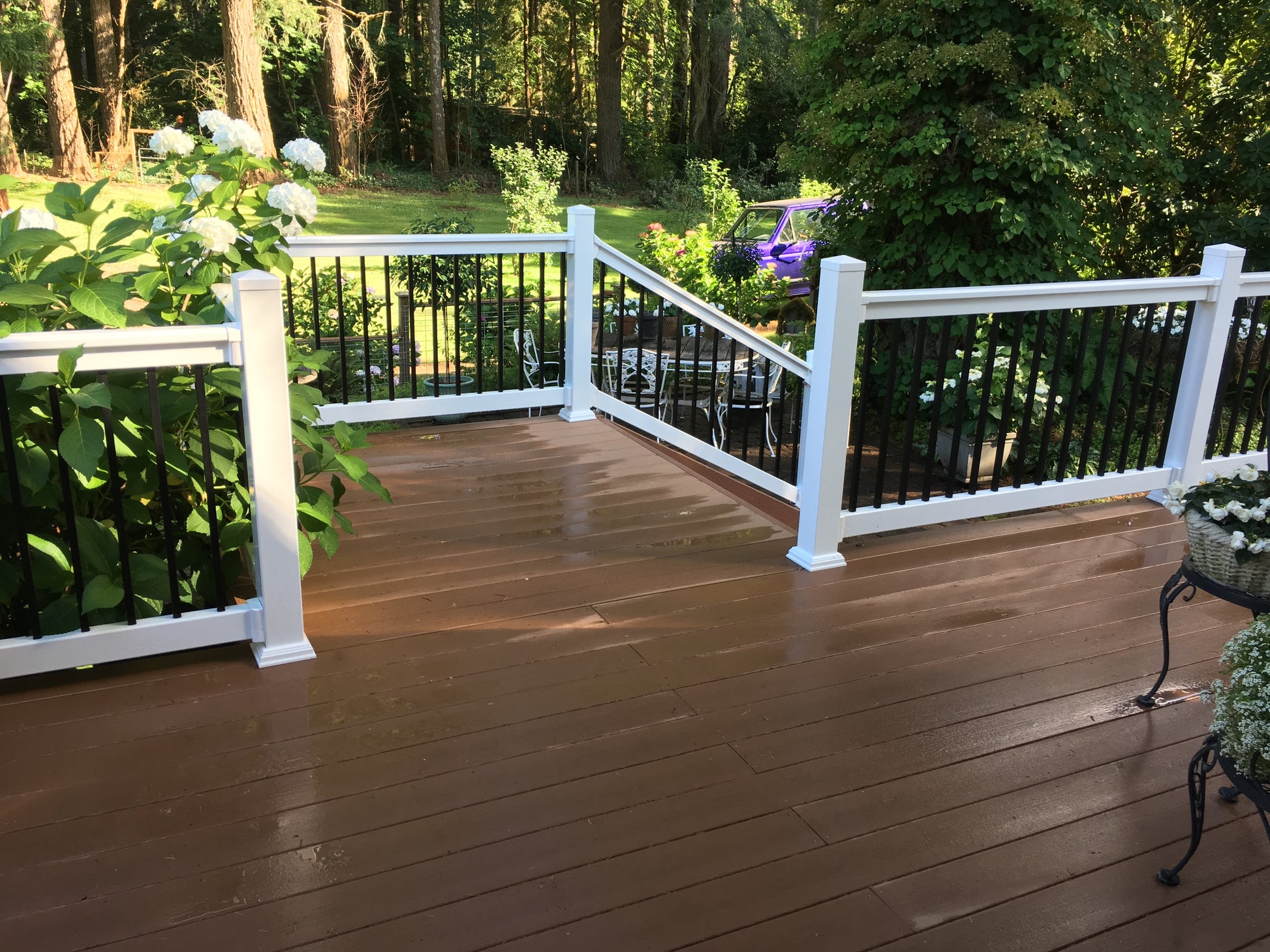Wooden deck with Weatherables Birmingham white vinyl deck railings and greenery in the background