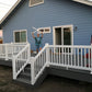 Person holding vinyl balusters on a blue house with white deck with a Weatherables Greenwich white vinyl deck railing.