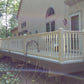 Deck with Weatherables Addison tan vinyl deck railing on a house surrounded by trees
