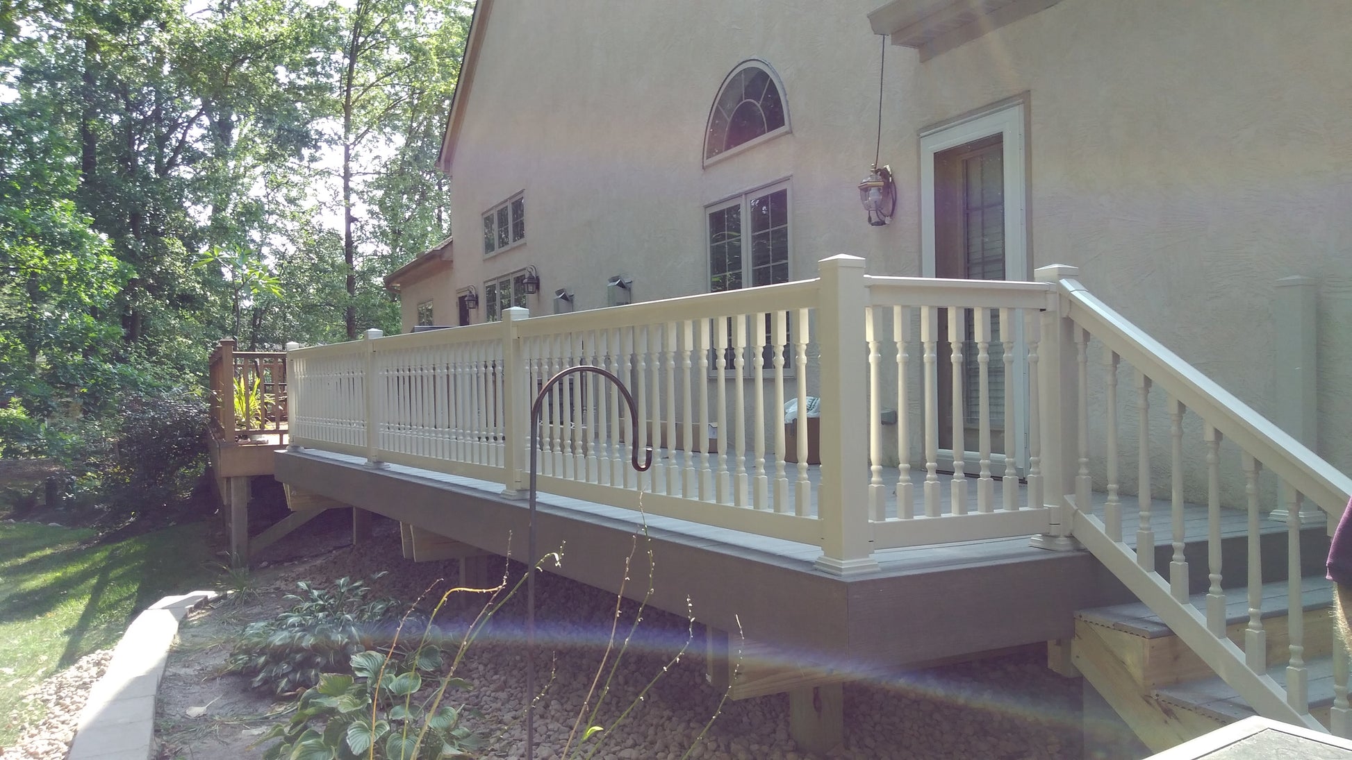 Deck with Weatherables Addison tan vinyl deck railing on a house surrounded by trees