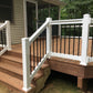Wooden deck with Weatherables Wiltshire white vinyl deck railing featuring black metal balusters, leading to a house.