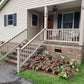 Front porch of a house with steps leading up to it, surrounded by greenery and Weatherables Yorkshire khaki vinyl stair railing