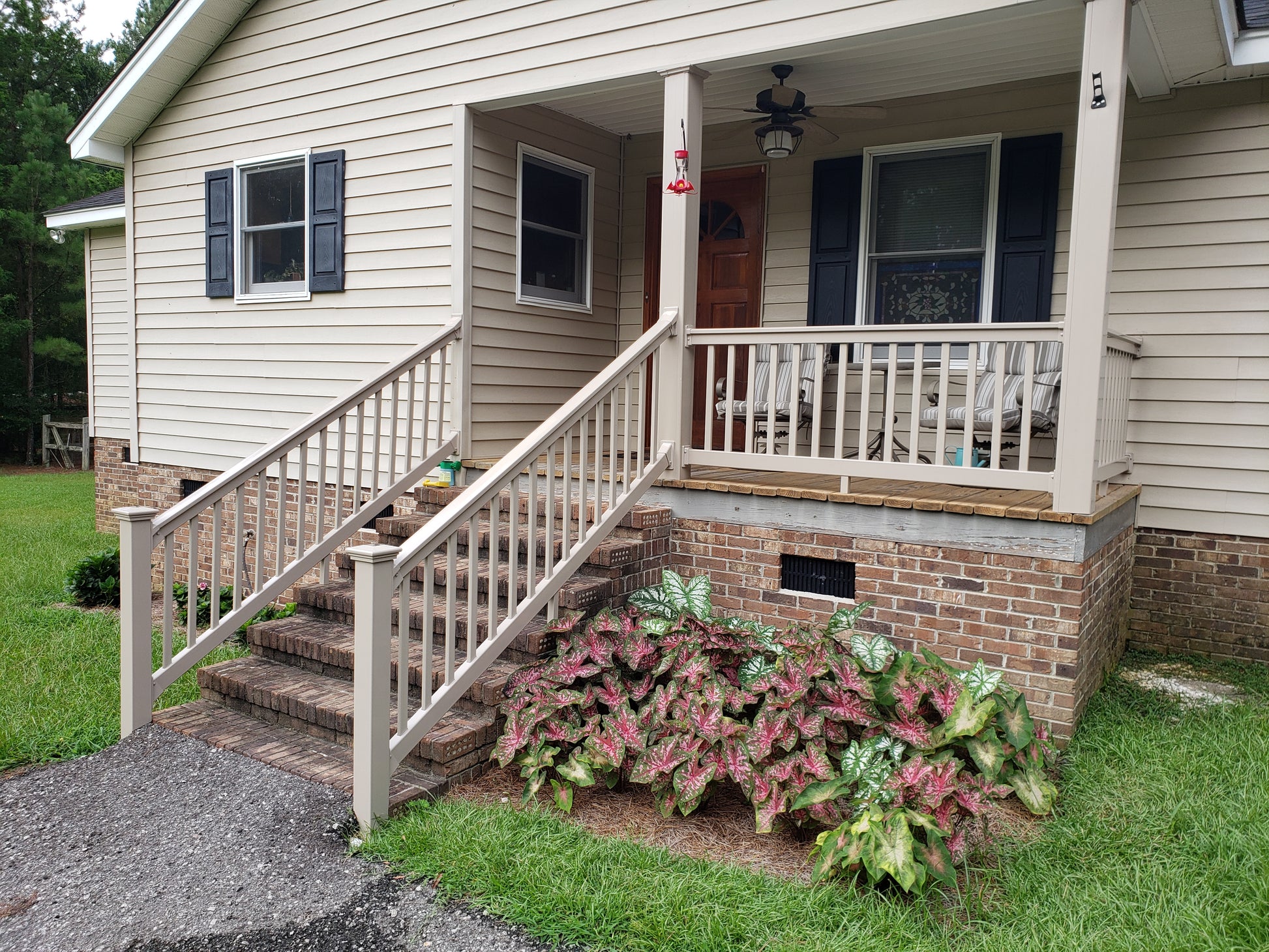 Front porch of a house with steps leading up to it, surrounded by greenery and Weatherables Yorkshire khaki vinyl stair railing