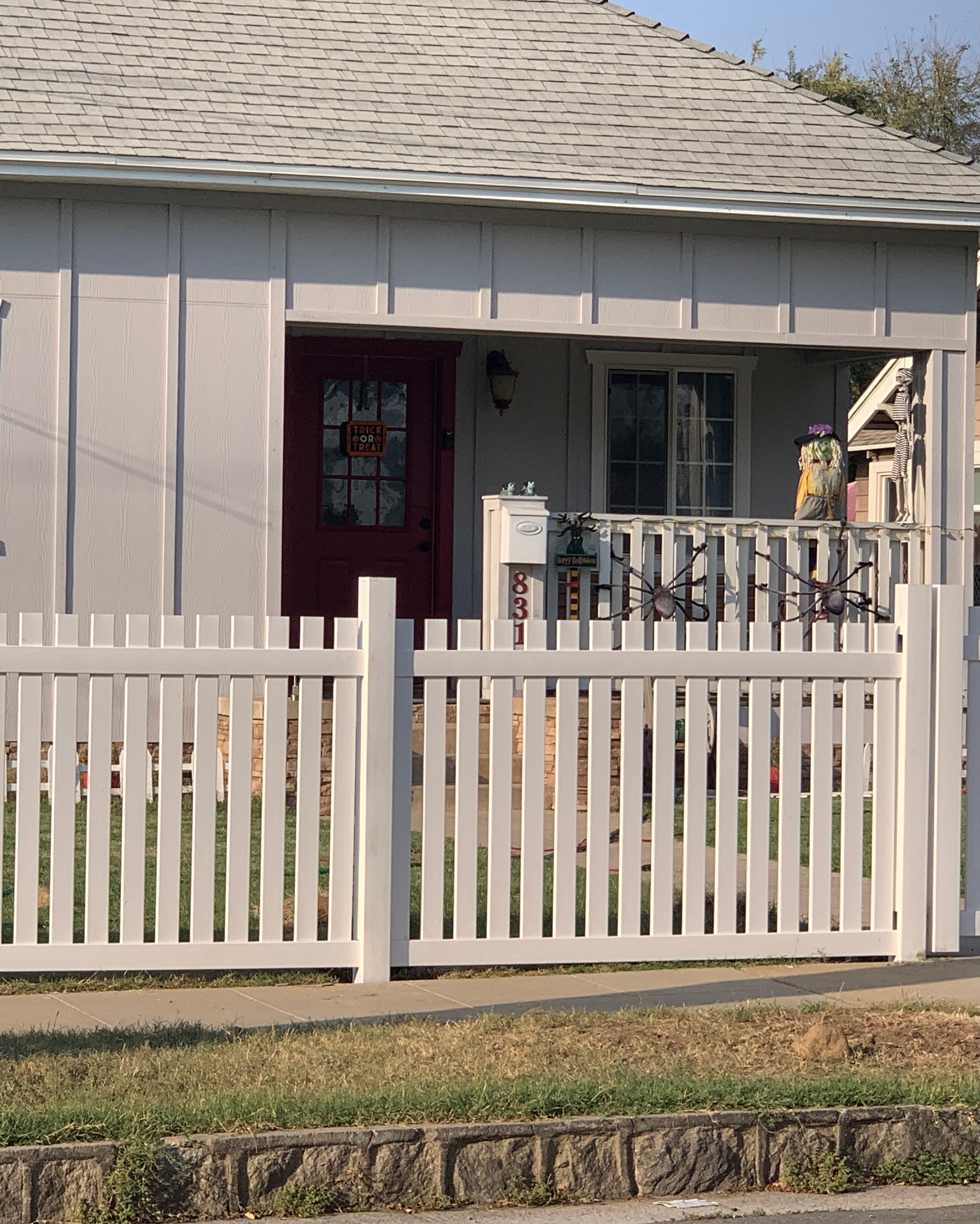 Weatherables Provinceown tan vinyl picket fence in front of a house with a red door.