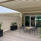 Outdoor patio area with Weatherables Davenport tan vinyl semi-privacy fencing,  pergola, table, chairs, and plants.